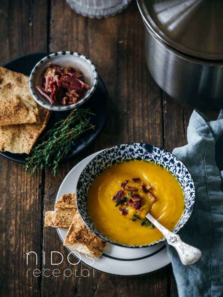 Pureed pumpkin soup in a bowl with pita cracker